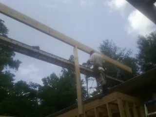 Carpenter setting a ridge beam over a new addition frame — Ice Dam Removal by Roofing Brothers in Faulkner