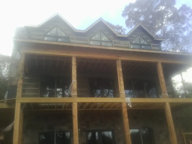 Dormers and porch framing on a large log home under construction — Roof Coating work by our crew in Faulkner