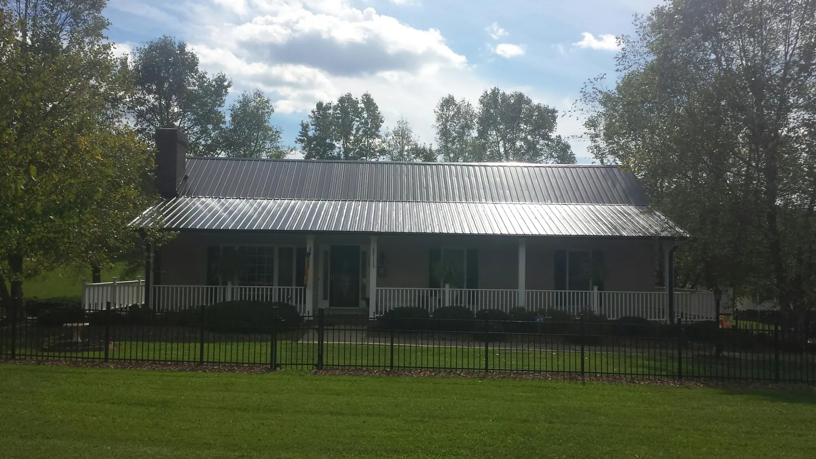 Gray metal roof on a brick ranch with a full width front porch — Gutter Guard Installation work by our crew in Faulkner