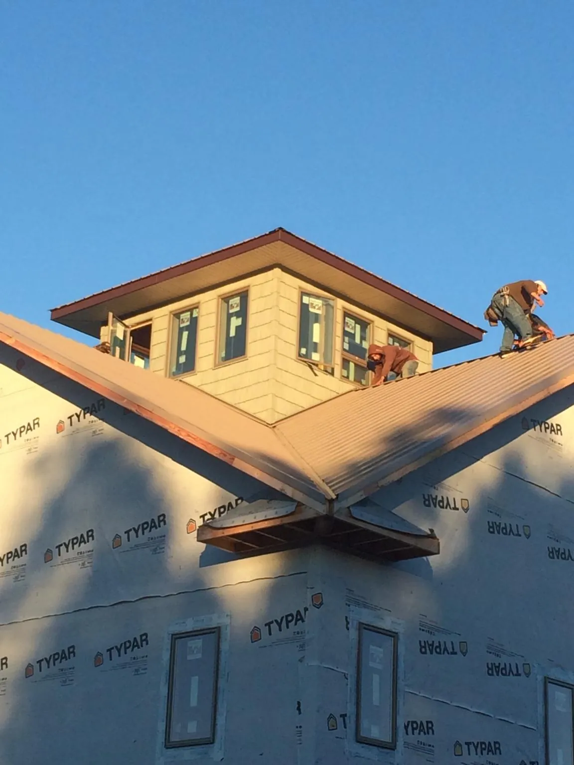 Roofers working around a rooftop cupola on a new metal roof at sunset — Roof Waterproofing in Faulkner by Roofing Brothers